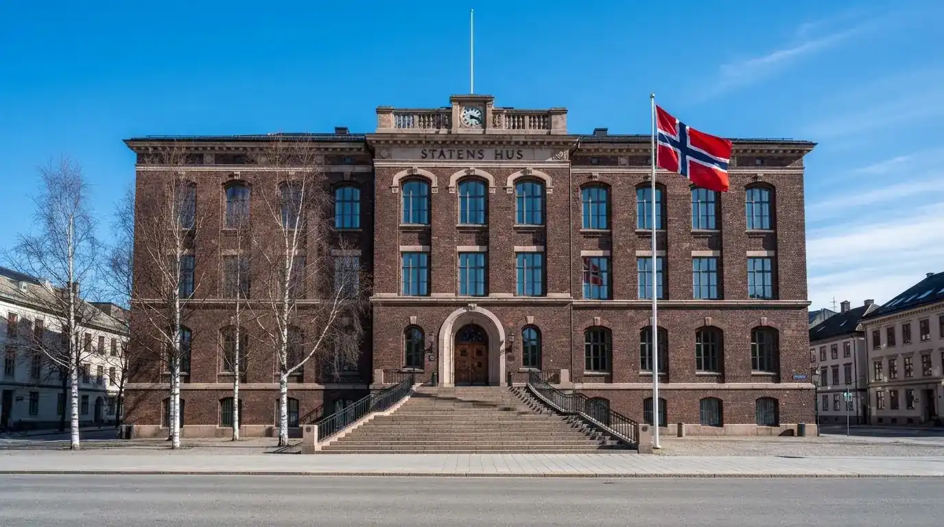 Offentlig kontorbygning i rødt murstein i en norsk by, med et flagg ved inngangen og blå himmel